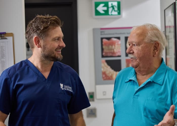 Tom Szarski talking with a smiling patient inside the clinic